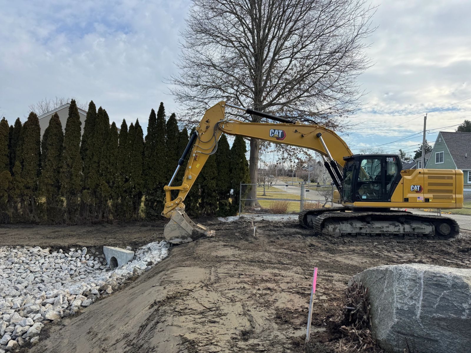 CAT excavator on a site prepared with stone stabilization and drainage pipe